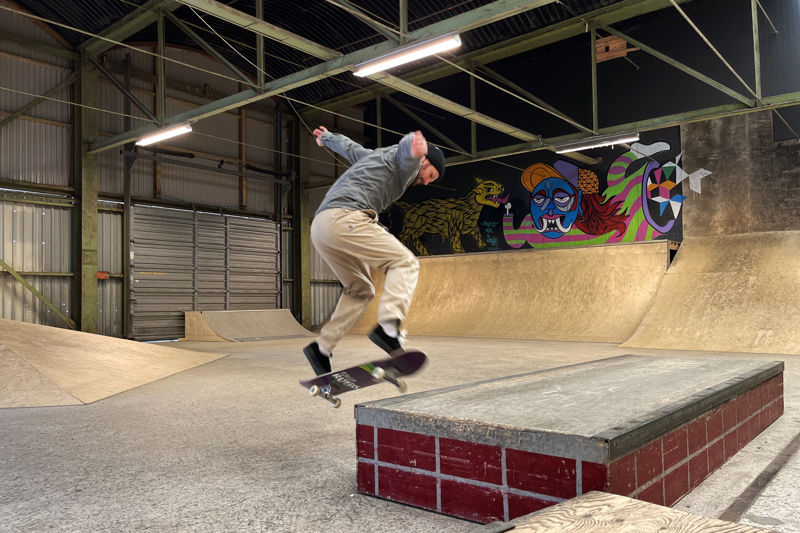 Ung mann trikser med skateboard. 