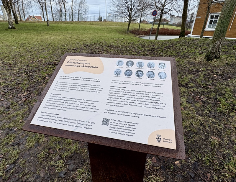 Skilt som har hvit bakgrunn, tekst i to spalter som forteller om motstandsbevegelse under krigen. Lys oransje øyform nederst i høyre hjørne med kommunelogo på. Overskrift på lys oransje bakgrunn øverst i venstre hjørne. QR-kode for mer informasjon. 