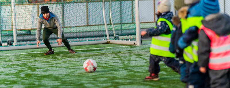 Mann i fotballmål og barn