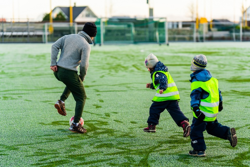 Voksen som spiller fotball med to barn