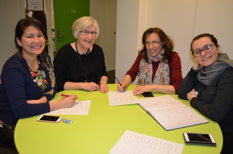 Lærer og tre voksne deltakere sitter sammen rundt et bord ved Johannes læringssenter for å undervise/lære.