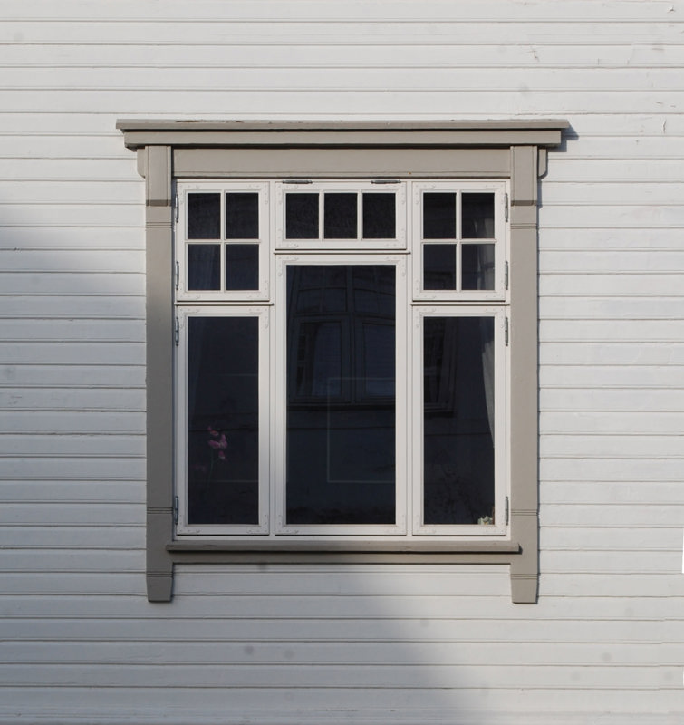 Et hvitt jugendvindu med grått jugendlistverk omkring.
