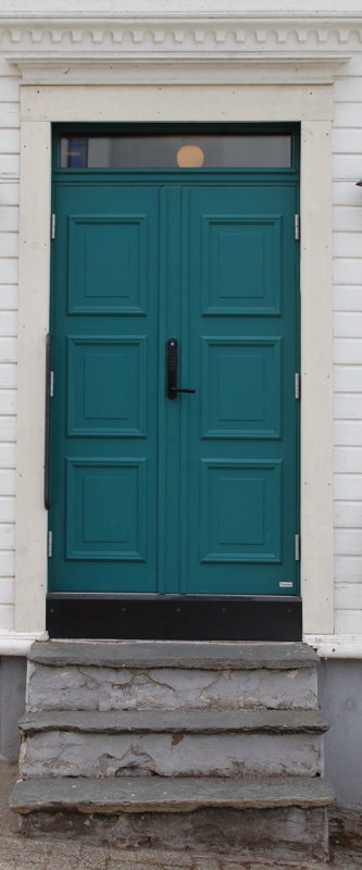 En turkis dør av komposittmateriale, over en gammel, murt trapp med skiferheller.