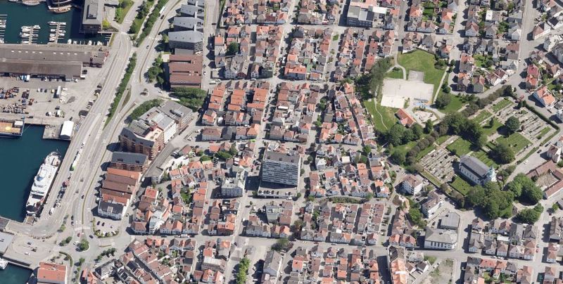 Et flyfoto over et byområde, med fergekai til venstre, Hetlandskirka til høyre.