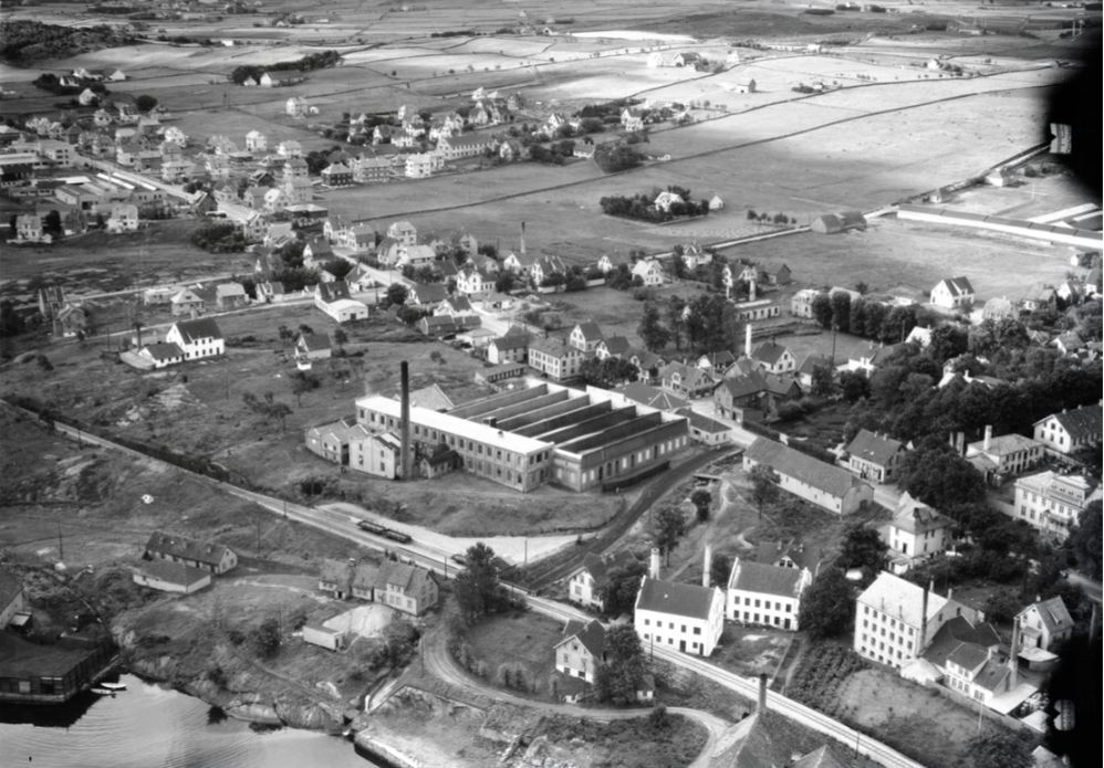 Et gammelt flyfoto av Hillevåg, med litt av Gandsfjorden synlig i nedre bildekant, og jordbruksland i øvre bildekant. Imellom ligger bebyggelsen langs både jernbanen og Hillevågsveien, med flere fabrikkbygninger så vel som boliger. Den største fabrikkbygningen i bildet er ullvarefabrikken Hillevaag og Olte.