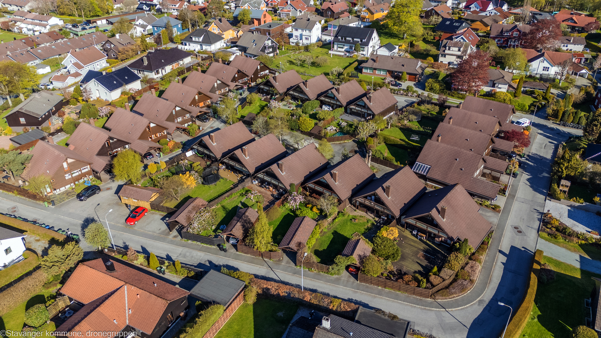Dronebilde som viser et tjuetalls hus i kjede, formet rundt felles tun.