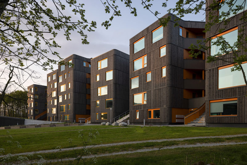 Blokker i mørkt tre, med oransje vinduskarmer.