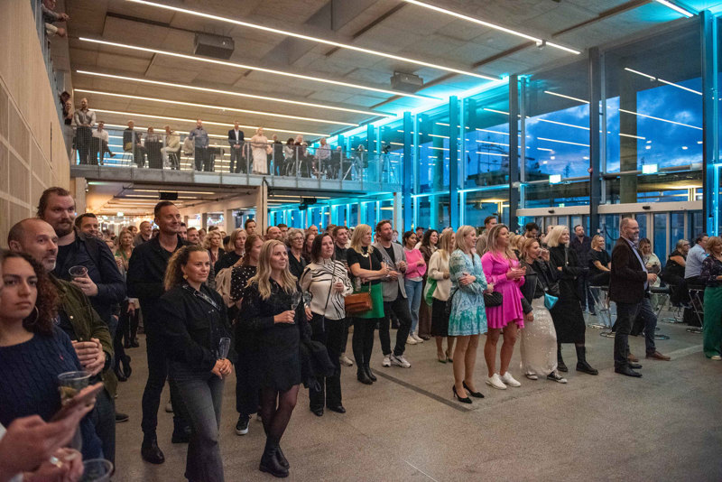 Bilde av publikum inne på nye Fiskepiren, som er et eksempel på prinsippet menneskelig: Revitaliseringen av hurtigbåtterminalen som konsertarena og konferansested har gitt sentrumen ny møteplass, samtidig som de reisende fortsatt tas vare på. Den nye bruken er en destinasjon som beriker sentrumslivet. Arkitekt: Alice Sturt /Brandsberg Dahls og MAD. Foto: Kyrre Sundal. 