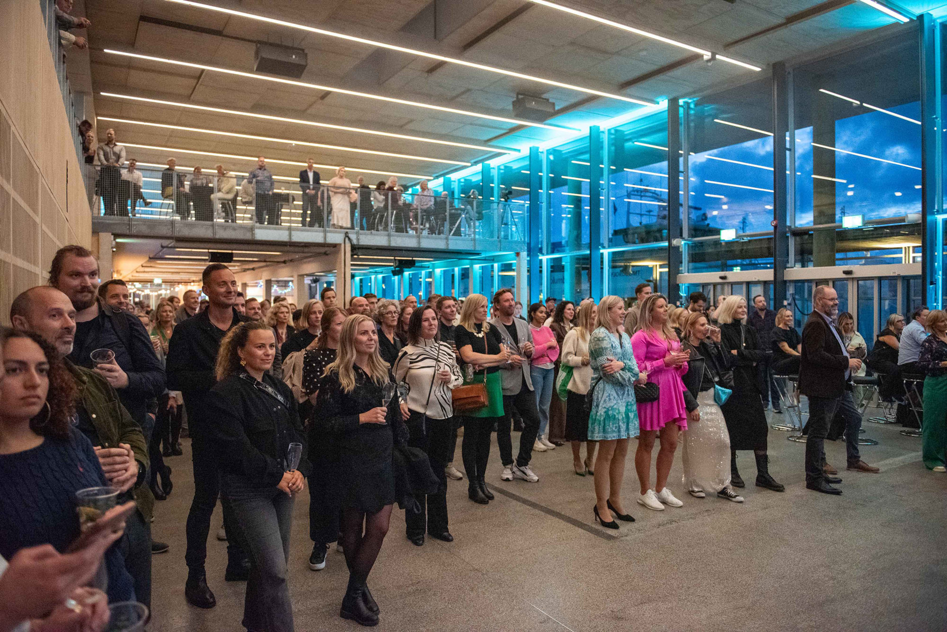 Bilde av publikum inne på nye Fiskepiren, som er et eksempel på prinsippet menneskelig: Revitaliseringen av hurtigbåtterminalen som konsertarena og konferansested har gitt sentrumen ny møteplass, samtidig som de reisende fortsatt tas vare på. Den nye bruken er en destinasjon som beriker sentrumslivet. Arkitekt: Alice Sturt /Brandsberg Dahls og MAD. Foto: Kyrre Sundal.