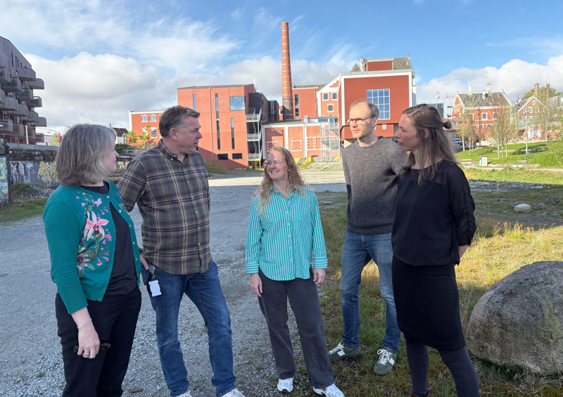 Fem personer med kulturbygget Tou i bakgrunnen. 