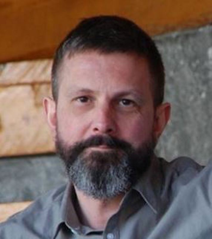 Ansiktet til hyggelig mann med kort mørkt hår og skjegg