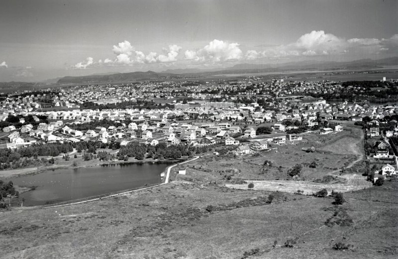 Flyfoto i svart hvitt over et tjern med park rundt og bebyggelse rundt parkområdet.