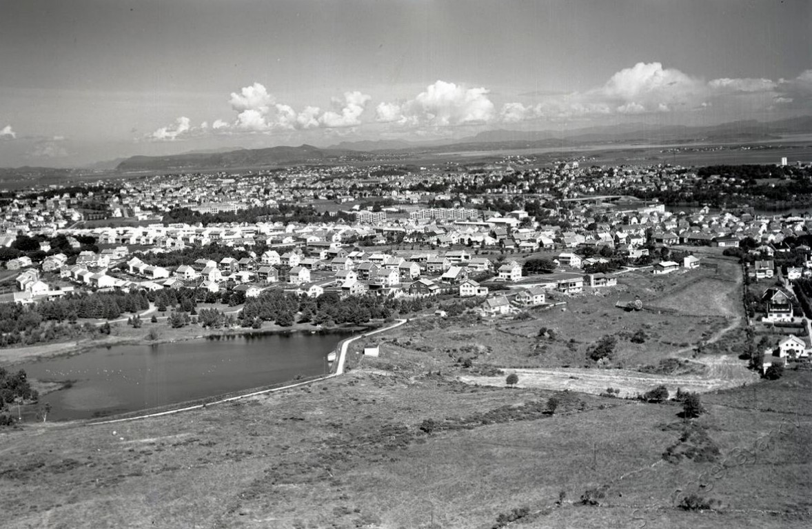 Flyfoto i svart hvitt over et tjern med park rundt og bebyggelse rundt parkområdet.