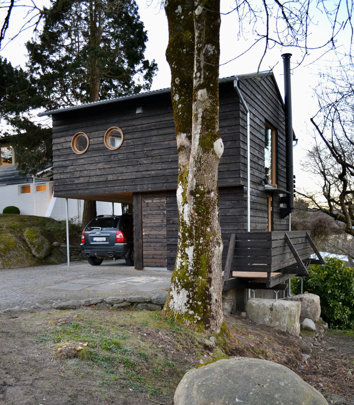 Bilde av anneks av tre, med runde vinduer i andre etasje og carport i deler av første etasje