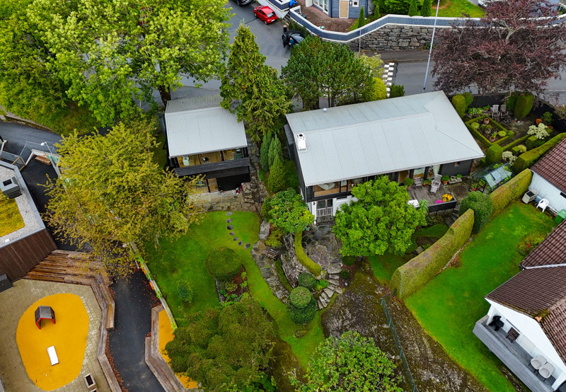 Dronefoto av boligområde der vi ser at arkitekstudioet deler hage med hovedhuset på eiendommen. 