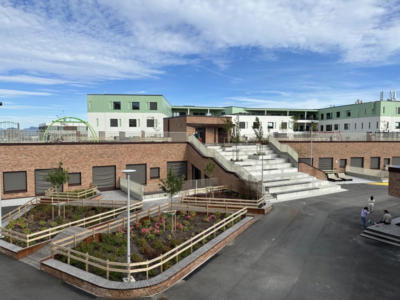 Skolegård med amfi i trappene, asfalt på bakken og vegger kledd med tegl. 