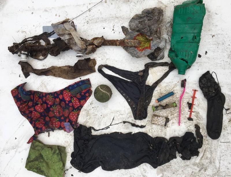 Skittent avfall som er hentet opp fra avløpsvann i kloakkrør ligger på et hvitt underlag. En liten ball, en truse, en sokk, plastemballasje, en ødelagt flaske, en lighter med mer.