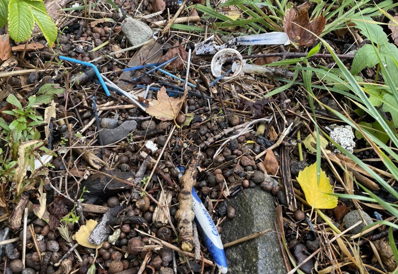 Nærbilde av strand med småstein iblandet søppel som q-tips, tannkostrester, emballasje og annet typisk baderomsavfall.