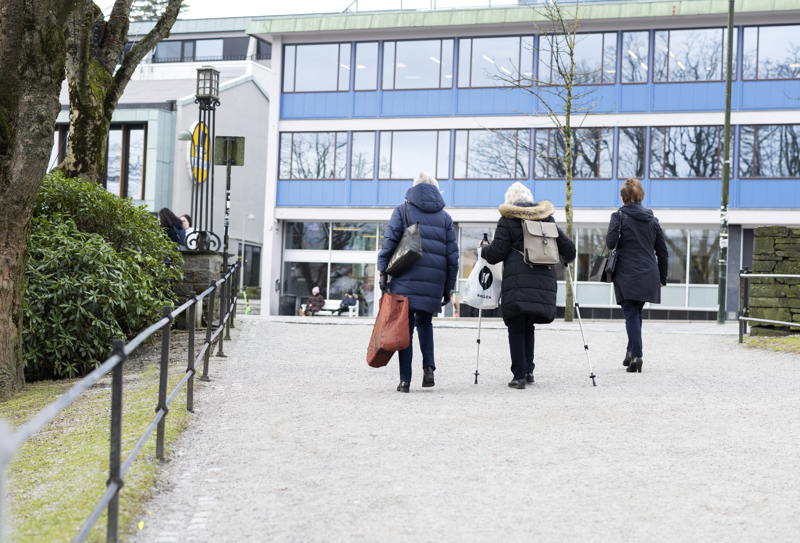 Tre eldre damer går i bredden. Fotografert bakfra.