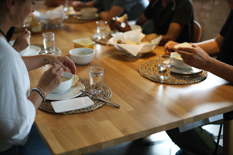 Flere personer sitter ved et bord og spiser suppe. 