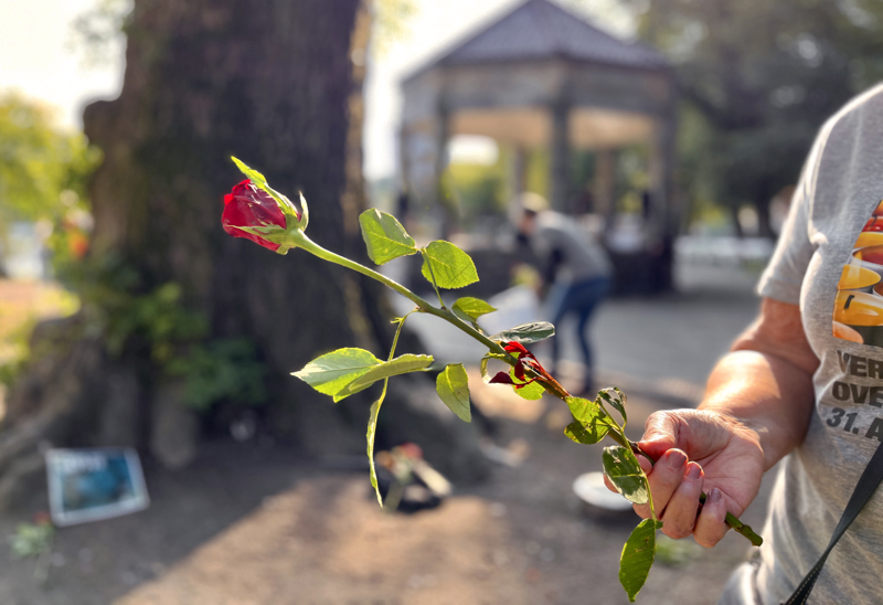 En person som holder en rose i hånden under markeringen i byparken i fjor.