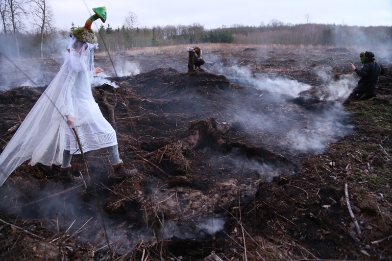 Fire personer med kostymer i et tåkefullt landskap.