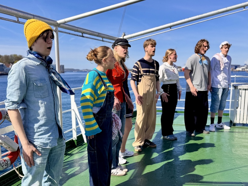 Mannskapet på MS Souvenir ønsker velkommen med en gammel engelsk sjanti, en arbeidssang, i strålende sol. 