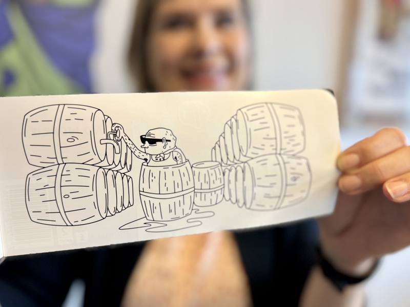 Person holder opp tegning av person  med bryggeritønner.