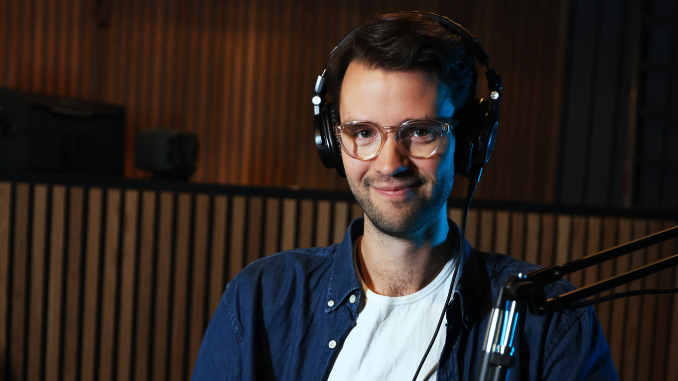 Christian Gilsvik smiler til kamera. Han har på seg podkastutstyr.