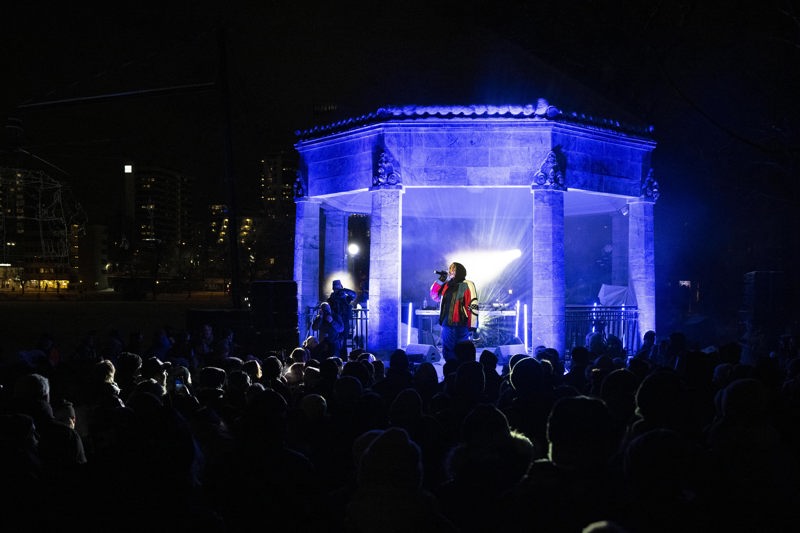 Folk i siluett som hører på artisten Izabell som synger.