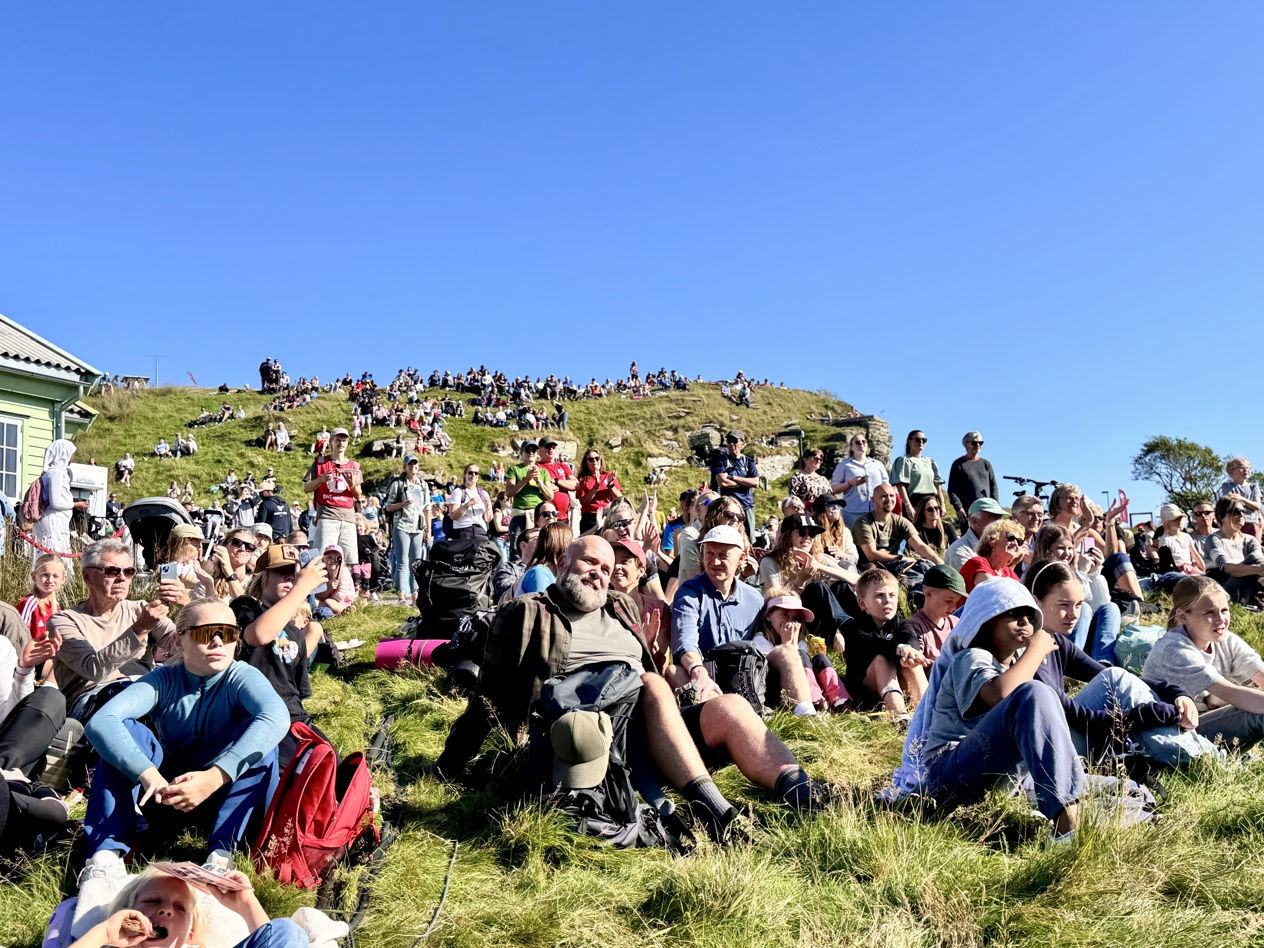 Mennesker i turklær sitter oppover i terrenget.
