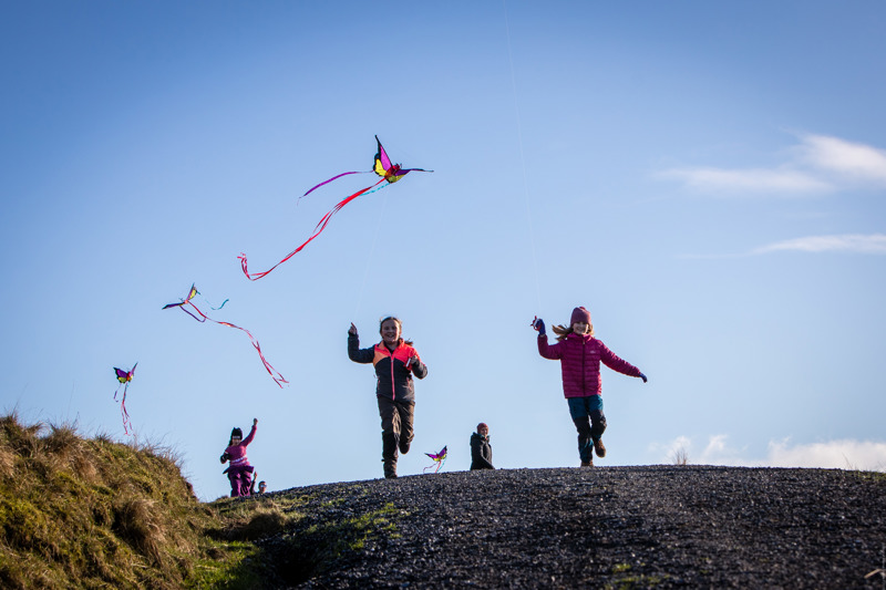 Bildet viser barn som løper med drager på Fjøløy.