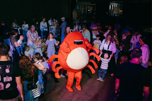 Barn danser rundt noen som er ikledd et hummerkostyme.