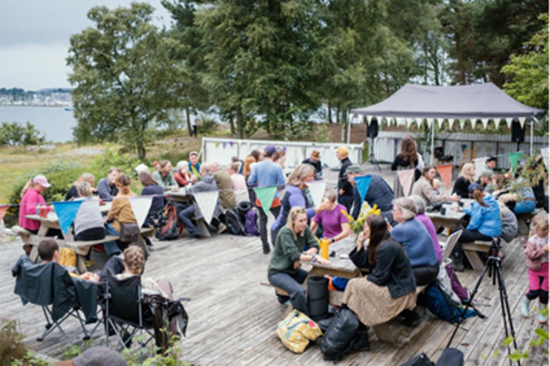 Ull og regnkledde mennesker sitter på benker utendørs. 