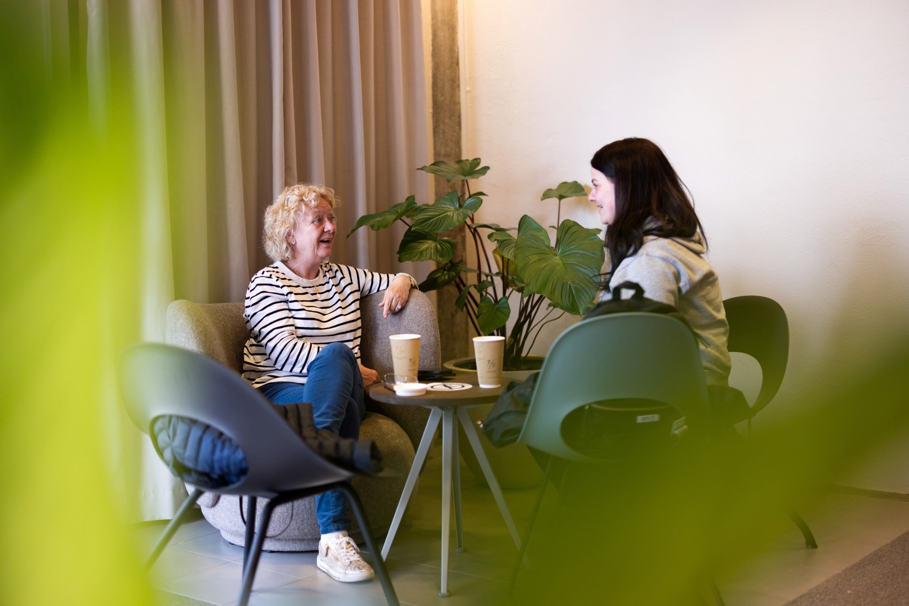 Vi ser to damer, en litt eldre og en litt yngre som koser seg sammen med et bort på Sølvberget med kaffe.