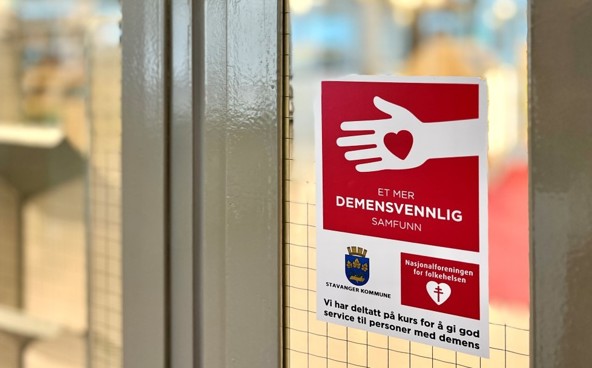 Vi ser bildet av en av inngangsdørene til Sølvberget bibliotek. Et stort rødt og hvitt klistremerke forteller at stedet er sertifisert demensvennlig.