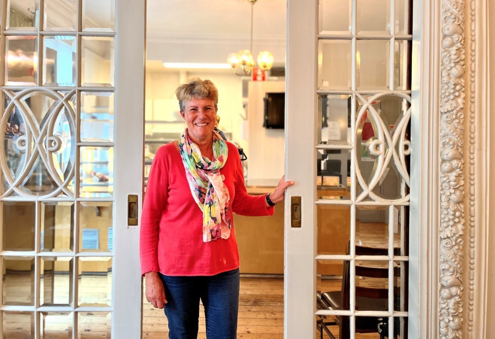 Vi ser et bilde Brit Bjørkli som driver Tante Emmas Hus. Hun står i døråpningen inn til kafeen.