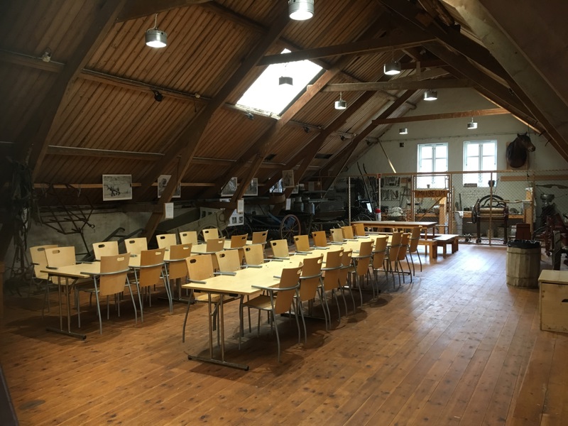 Bildet viser bord og stoler i et stort rom.