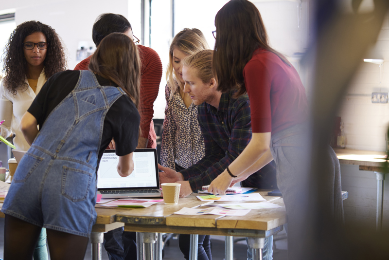 Gruppe unge mennesker som ser på en pc skjerm