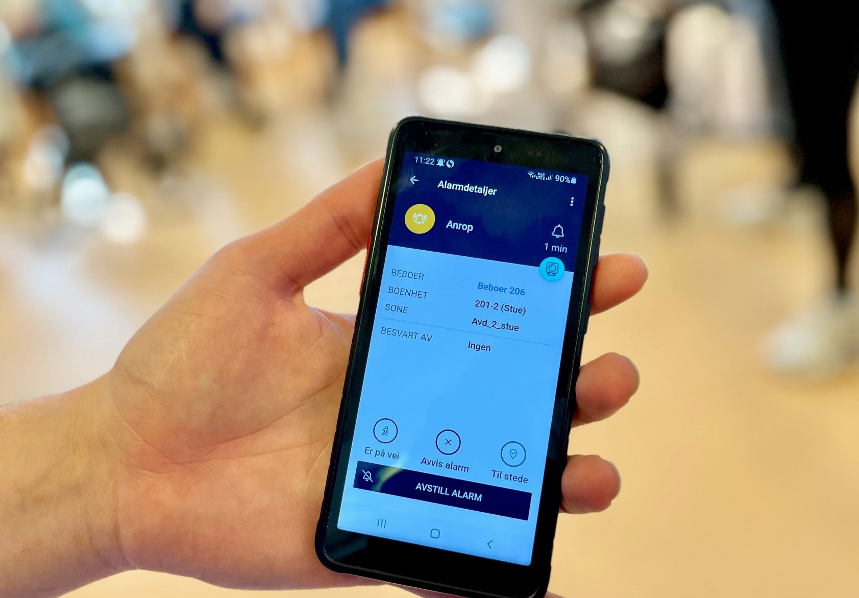 Bildet viser en telefon med en melding på skjermen som beskriver hvor en pasient som trenger hjelp befinner seg.
