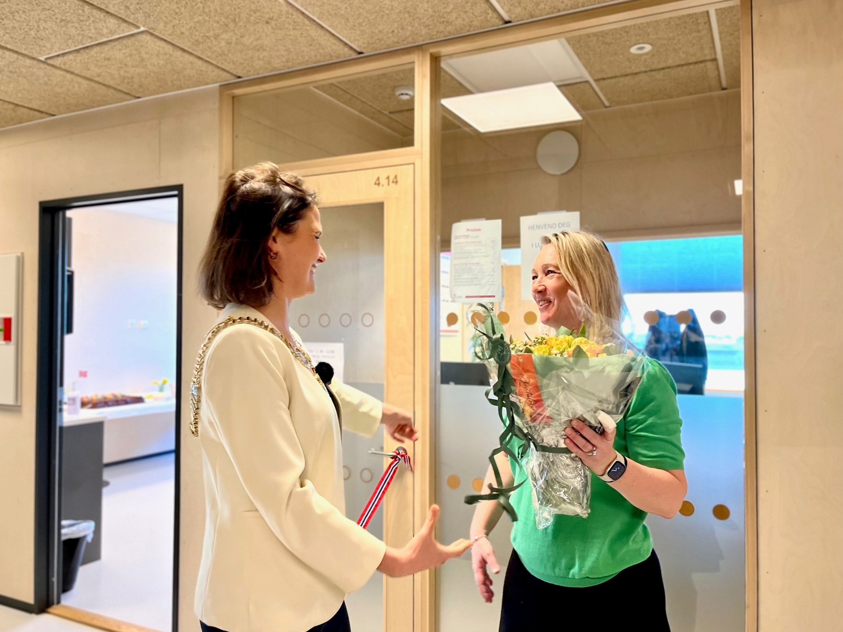 Vi ser to personer. Den ene gir en blomsterbukett til den andre for å feire.