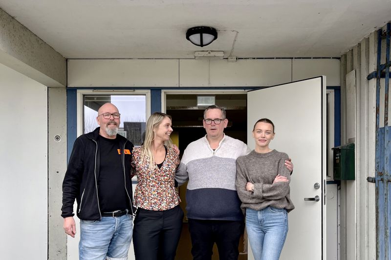 Fire personer står skulder ved skulder foran inngangen til aktivitetskafeen.