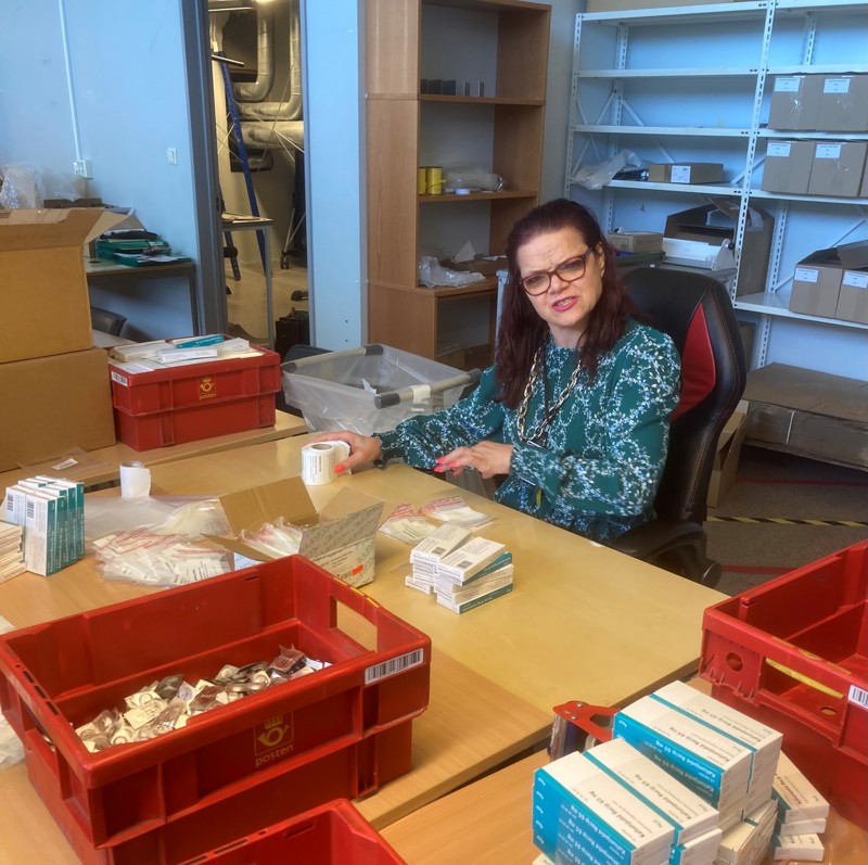 Elisabeth hos Attende pakker jodtabletter i små plastposer. Elisabeth har mørkt langt hår og briller.