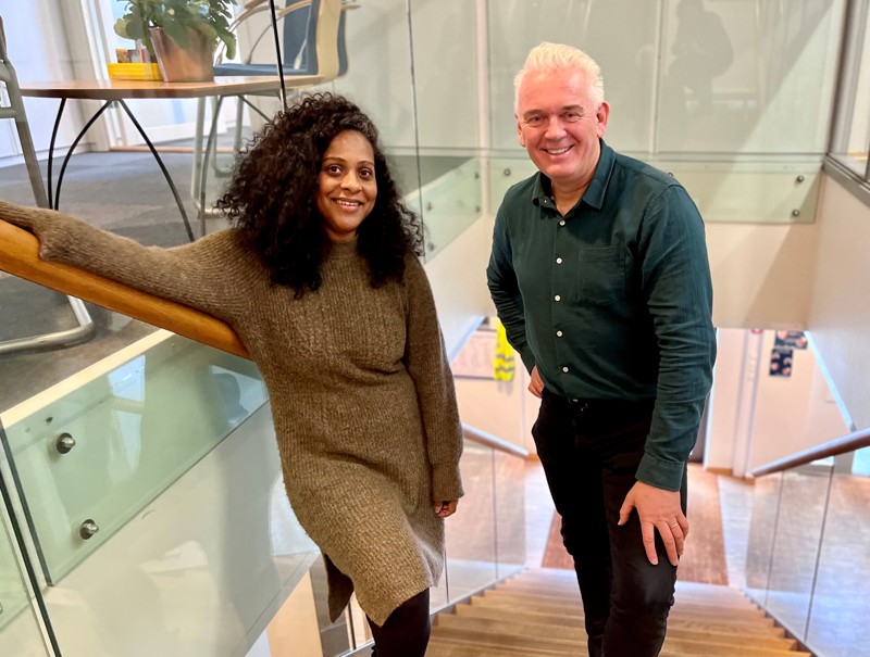 Bildet viser Janne Rage og Tor Arne Hartvigsen som står ved siden av hverandre i  trappen i kontorlokalene til flyktningtjenesten. 