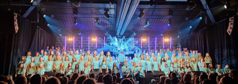 Bildet viser alle revydeltakerne på scenen i turkise t-skjorter.