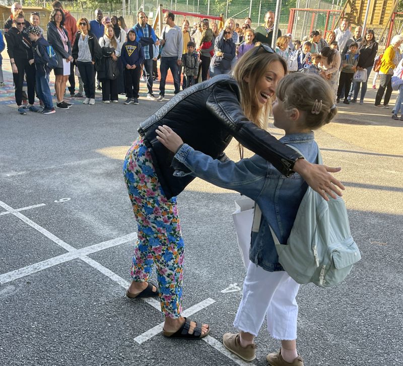 En mor gir et barn en klem i skolegården på Johannes læringssenter.