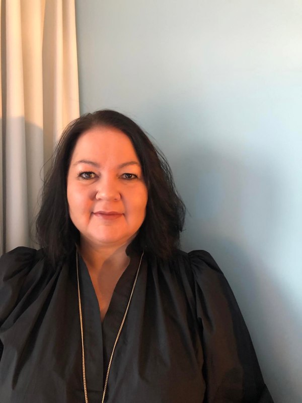 Portrettbilde av Stina Løkke. Hun har halvlangt mørkt hår.