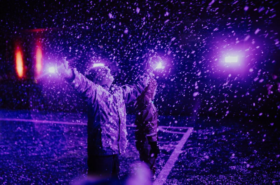 Et barn som strekker hendene i været, i lilla lys. Foto: Line Owren