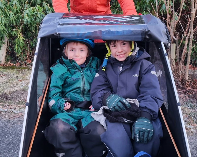 to gutter i kassa på lastesykkel. smiler