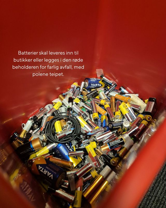 En rød beholder fylt med brukte batterier av ulike typer og størrelser, samt noen ledninger. Teksten på bildet informerer om at batterier skal leveres til butikk eller legges i rød beholder for farlig avfall, med polene teipet